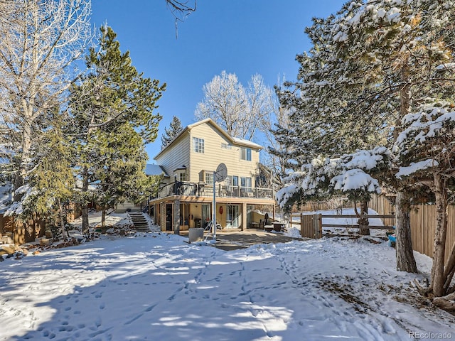 snow covered back of property featuring a wooden deck