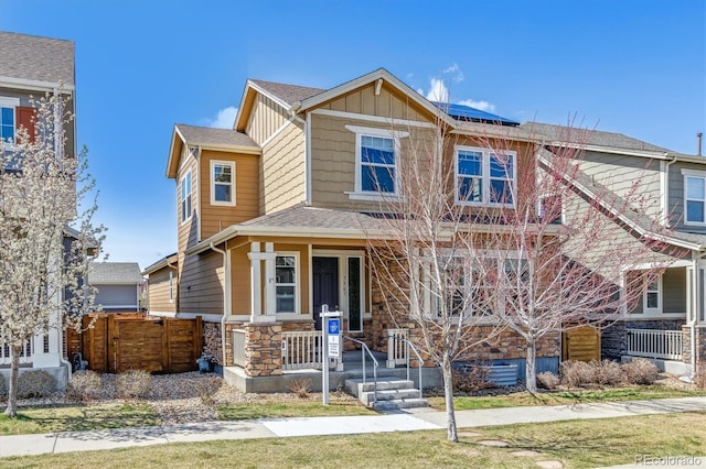 7367 S Pennsylvania St, Littleton, CO 80122 - craftsman-style home with covered porch, stone siding, solar panels, board and batten siding, and fence