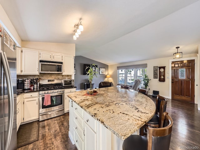 9150 Garrison St, Broomfield, CO 80021 - kitchen with appliances with stainless steel finishes, dark wood-type flooring, backsplash, a kitchen island, and light stone counters