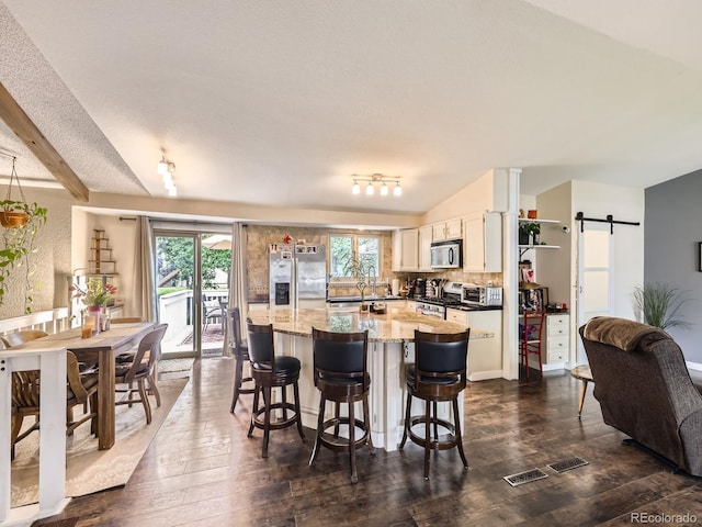 9150 Garrison St, Broomfield, CO 80021 - kitchen with appliances with stainless steel finishes, dark wood-style flooring, a kitchen island, a barn door, and a breakfast bar
