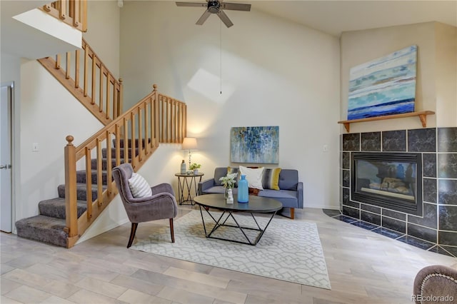 living room featuring a tile fireplace, hardwood / wood-style flooring, ceiling fan, and lofted ceiling