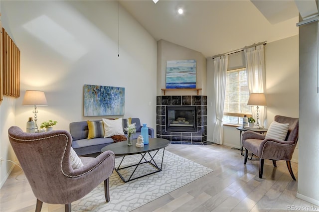 living room featuring a fireplace, high vaulted ceiling, and light hardwood / wood-style flooring