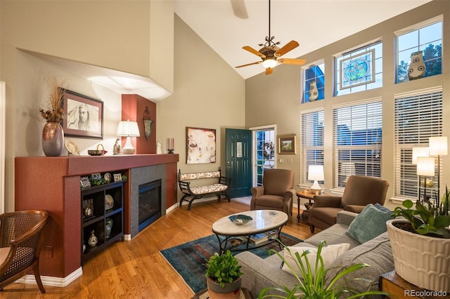 living room with hardwood / wood-style flooring, high vaulted ceiling, a tile fireplace, and ceiling fan