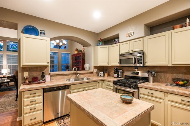 kitchen with a kitchen island, appliances with stainless steel finishes, sink, and tile counters