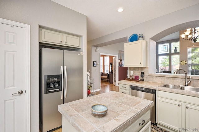 kitchen with sink, backsplash, stainless steel appliances, tile counters, and a chandelier