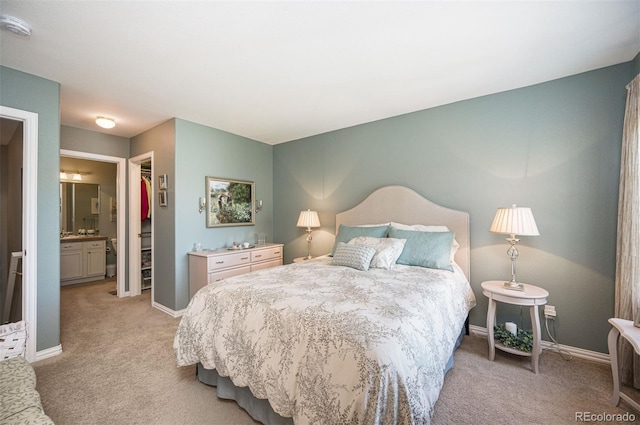 bedroom featuring light colored carpet, ensuite bathroom, a spacious closet, and a closet