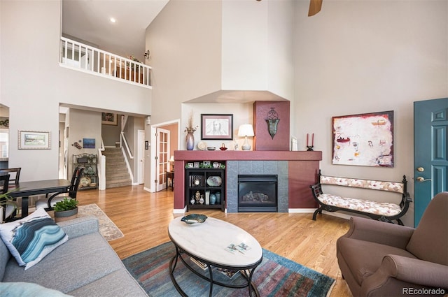 living room with hardwood / wood-style floors, a tile fireplace, and a high ceiling