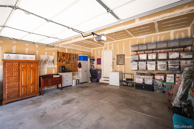 garage featuring white refrigerator and a garage door opener