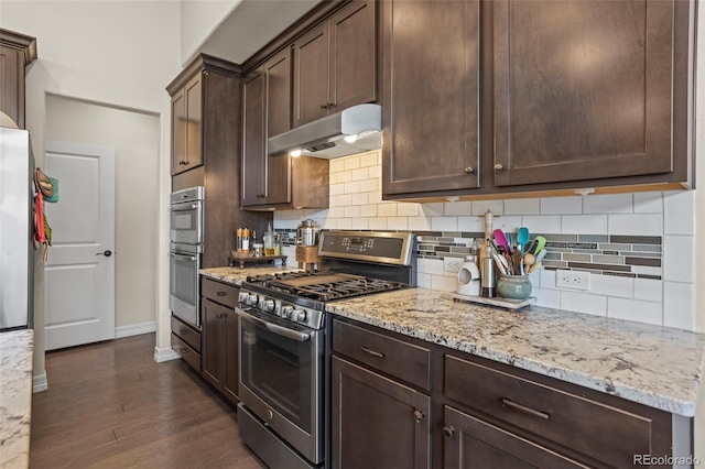 13833 Rivercrest Cir, Colorado Springs, CO 80921 - kitchen featuring under cabinet range hood, stainless steel appliances, dark brown cabinets, baseboards, and backsplash