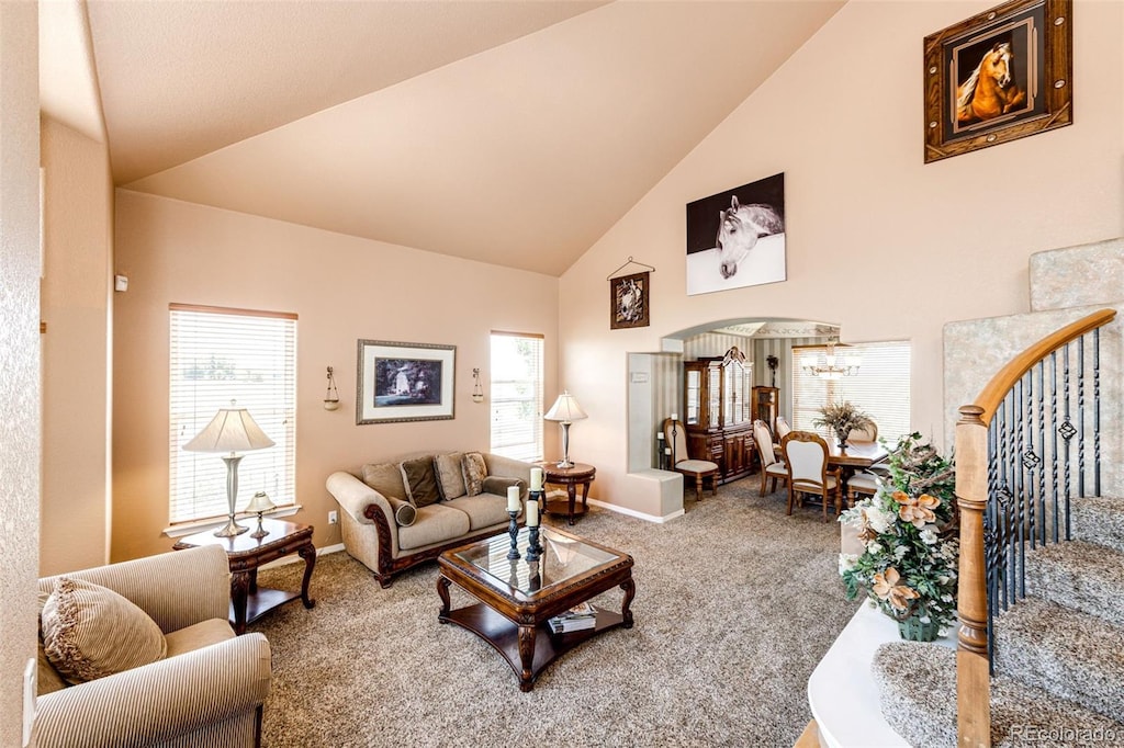 carpeted living room with an inviting chandelier and high vaulted ceiling