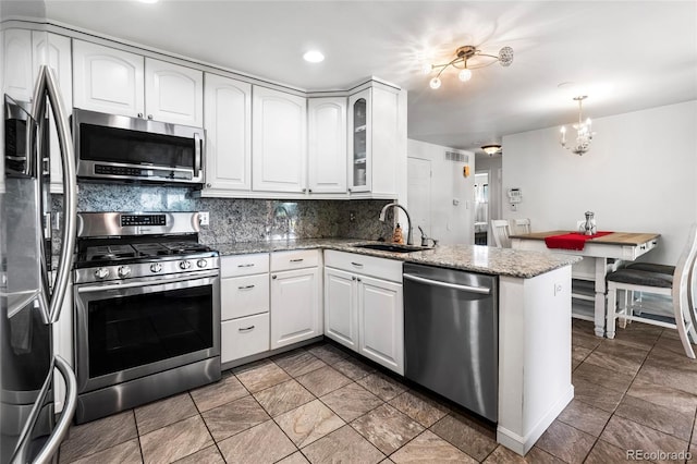 6336 W 71st Pl, Arvada, CO 80003 - kitchen featuring appliances with stainless steel finishes, a peninsula, tasteful backsplash, white cabinetry, and glass insert cabinets