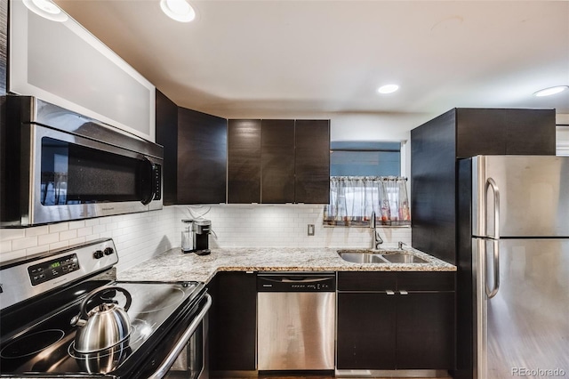 kitchen featuring light stone countertops, sink, decorative backsplash, and appliances with stainless steel finishes