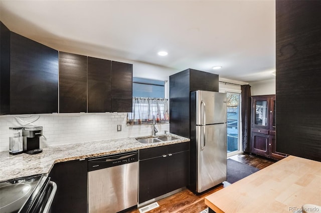 kitchen with decorative backsplash, sink, light stone countertops, stainless steel appliances, and dark hardwood / wood-style flooring