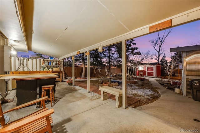 patio terrace at dusk with exterior bar and a storage unit