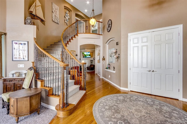 entryway featuring wood finished floors, a high ceiling, and baseboards