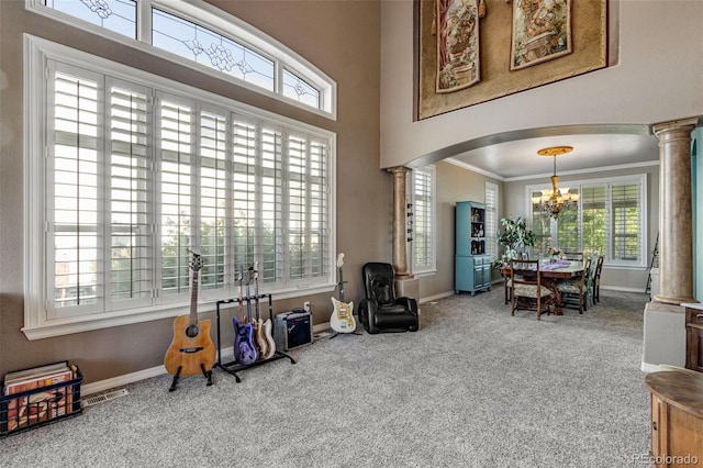 interior space featuring a wealth of natural light, ornate columns, carpet flooring, and an inviting chandelier