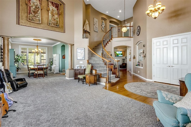 foyer with decorative columns, arched walkways, an inviting chandelier, and a towering ceiling