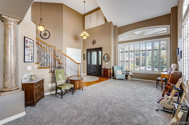 entryway with carpet flooring, baseboards, decorative columns, and a towering ceiling