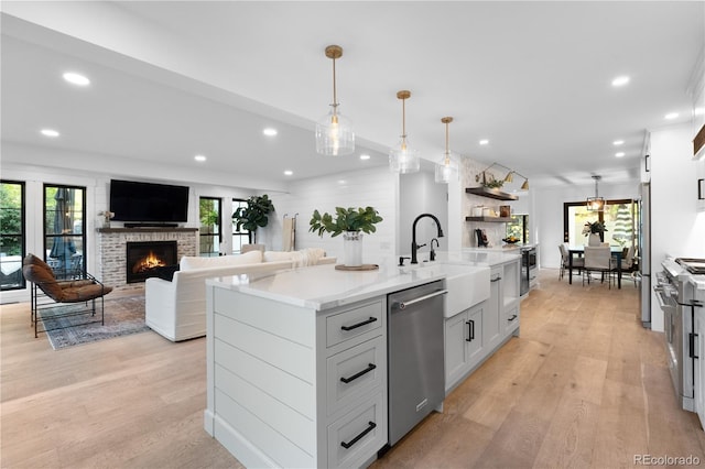 3235 E Easter Pl, Centennial, CO 80122 - kitchen featuring appliances with stainless steel finishes, recessed lighting, light wood finished floors, a brick fireplace, and pendant lighting