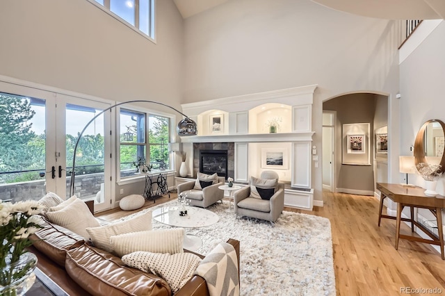 714 Skywalker Pt, Lafayette, CO 80026 - living area featuring a towering ceiling, light wood-style floors, a tile fireplace, and french doors