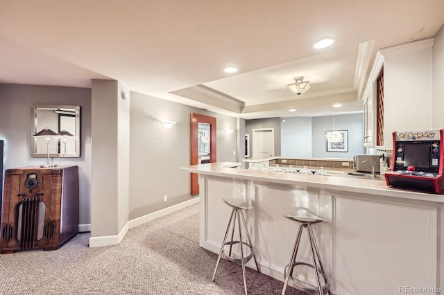 714 Skywalker Pt, Lafayette, CO 80026 - kitchen with a peninsula, a raised ceiling, light carpet, light countertops, and a kitchen bar