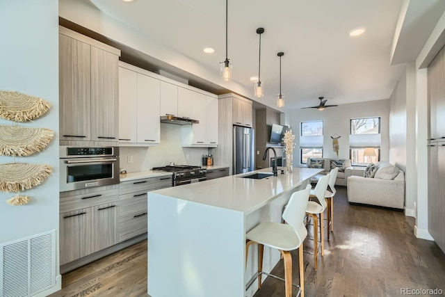 kitchen featuring sink, decorative light fixtures, a center island with sink, premium appliances, and a kitchen breakfast bar