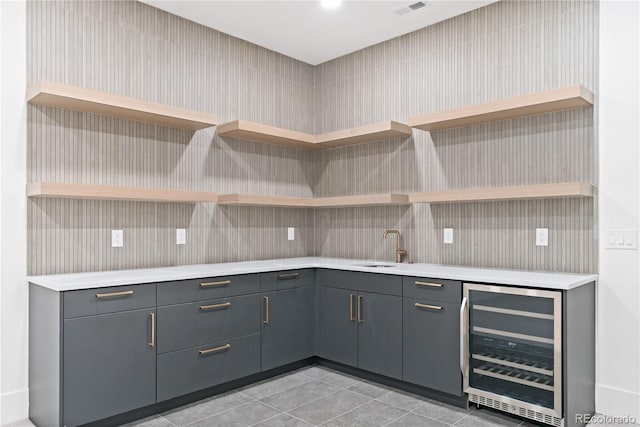 kitchen with wine cooler, sink, light tile patterned floors, and gray cabinetry