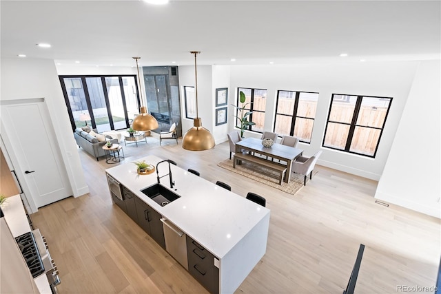 living room featuring light wood-type flooring, lofted ceiling, a healthy amount of sunlight, and sink