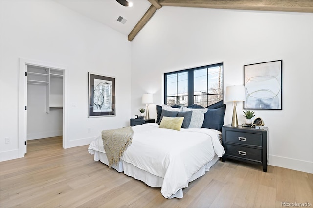 bedroom with a closet, light hardwood / wood-style floors, high vaulted ceiling, and a walk in closet