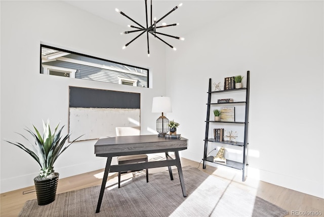 home office featuring light hardwood / wood-style flooring, a chandelier, and a high ceiling