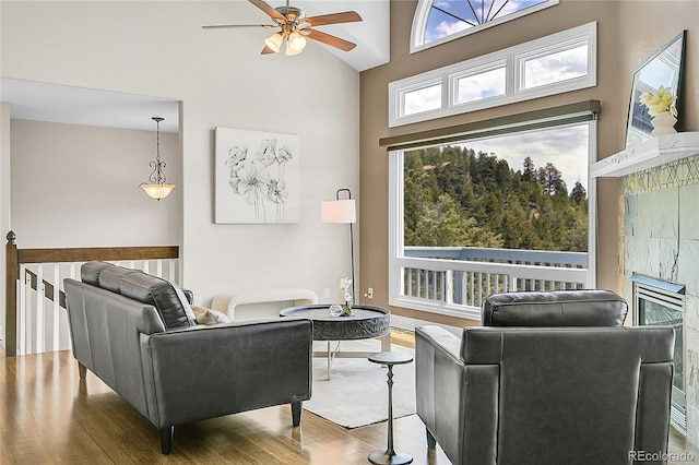 33633 Elk Run, Evergreen, CO 80439 - living room with wood finished floors, ceiling fan, a towering ceiling, and a tiled fireplace