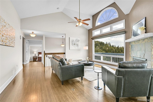 33633 Elk Run, Evergreen, CO 80439 - living area featuring high vaulted ceiling, wood finished floors, a ceiling fan, healthy amount of natural light, and a tiled fireplace