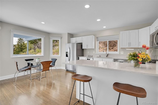 33633 Elk Run, Evergreen, CO 80439 - kitchen with stainless steel appliances, a sink, a breakfast bar, light stone counters, and recessed lighting