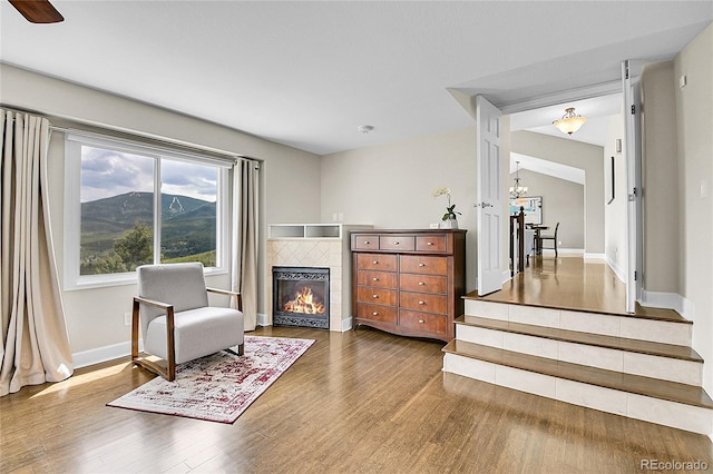 33633 Elk Run, Evergreen, CO 80439 - living area featuring a tiled fireplace, wood finished floors, baseboards, a chandelier, and a mountain view