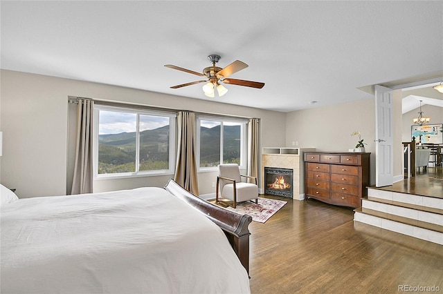 33633 Elk Run, Evergreen, CO 80439 - bedroom with wood finished floors, a fireplace, multiple windows, and a chandelier