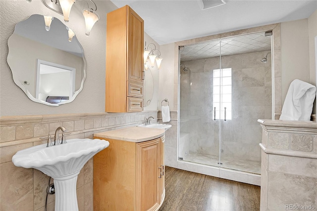 33633 Elk Run, Evergreen, CO 80439 - bathroom with tile walls, a shower stall, wood finished floors, a sink, and wainscoting