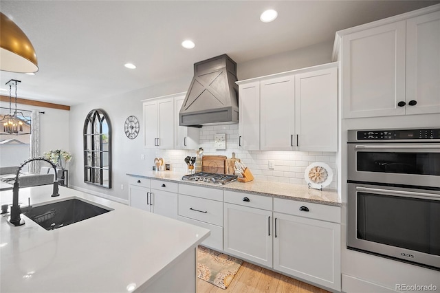 1485 Captiva Beach Ln, Monument, CO 80132 - kitchen featuring stainless steel appliances, custom exhaust hood, white cabinetry, backsplash, and light wood-type flooring