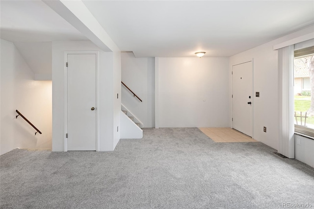 foyer entrance featuring stairway and carpet floors