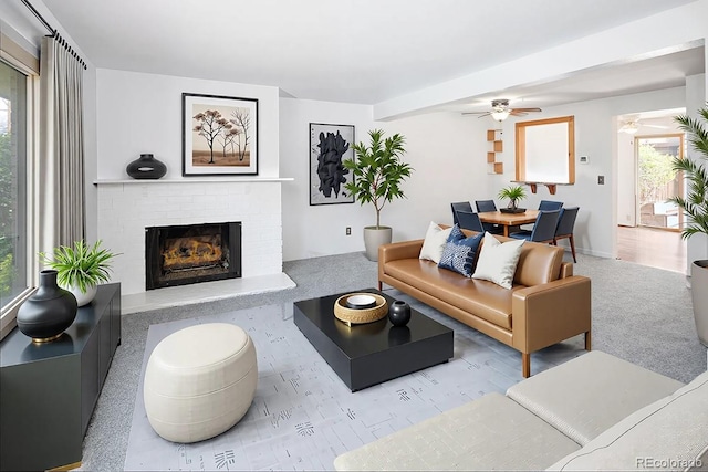 living area with a brick fireplace, a ceiling fan, and plenty of natural light