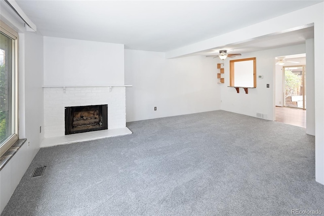 unfurnished living room featuring ceiling fan, carpet flooring, a fireplace, and visible vents