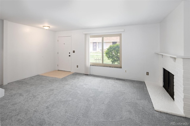 unfurnished living room with a fireplace, carpet floors, and visible vents