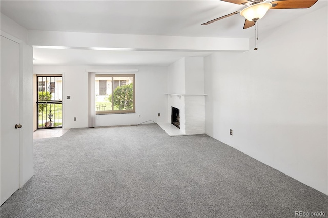unfurnished living room featuring a fireplace with raised hearth, ceiling fan, and light colored carpet