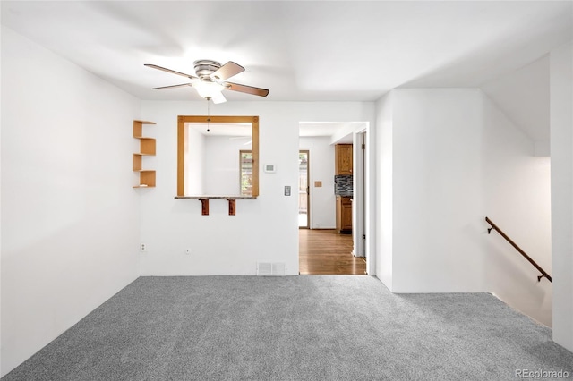 empty room featuring a ceiling fan, visible vents, and carpet floors