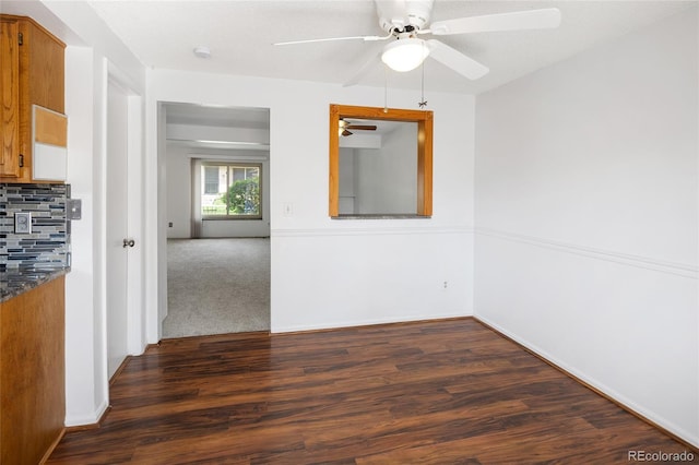 unfurnished room featuring a ceiling fan, dark wood-style flooring, and baseboards