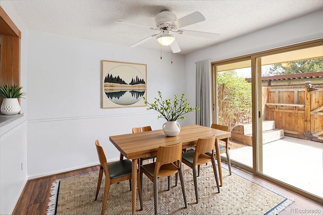 dining room featuring light wood finished floors, a textured ceiling, baseboards, and a ceiling fan