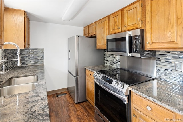 kitchen featuring baseboards, a sink, dark wood-type flooring, backsplash, and stainless steel appliances