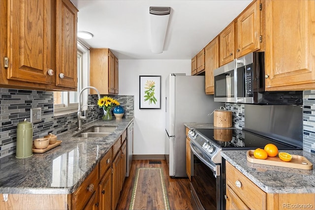 kitchen with a sink, stainless steel appliances, dark wood-style flooring, baseboards, and tasteful backsplash
