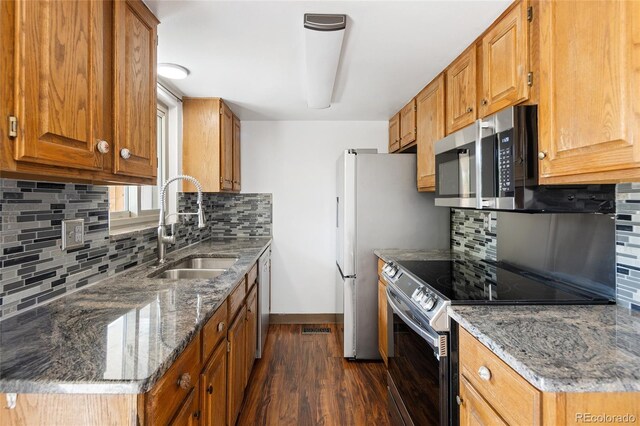 kitchen with baseboards, dark wood-style flooring, a sink, backsplash, and stainless steel appliances