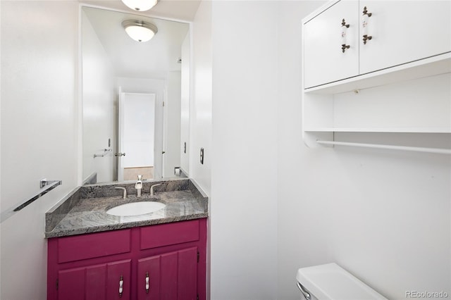 half bathroom featuring vanity and toilet
