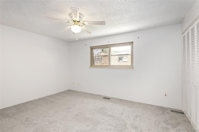 unfurnished bedroom featuring carpet, a textured ceiling, a closet, and visible vents